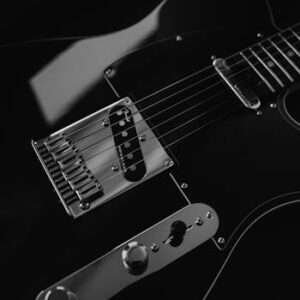Detailed black and white close-up of an electric guitar, highlighting strings and hardware.
