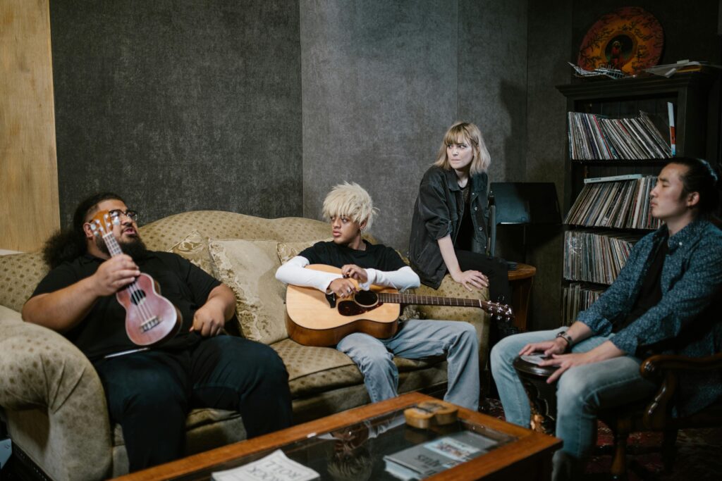 Musicians gathered in a cozy studio with guitars, creating music together.